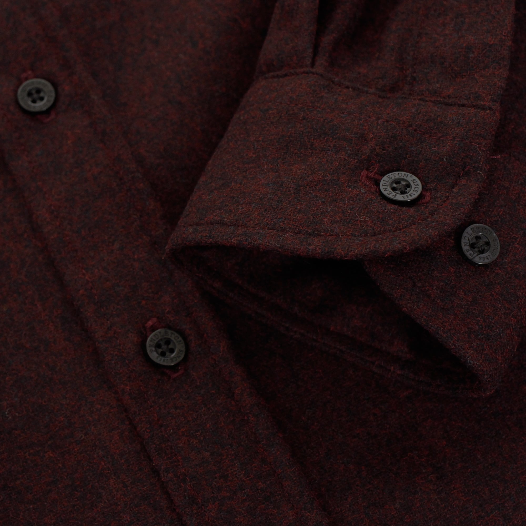 A detailed close-up of the dark red shirt's cuffs with visible buttons and stitching.
