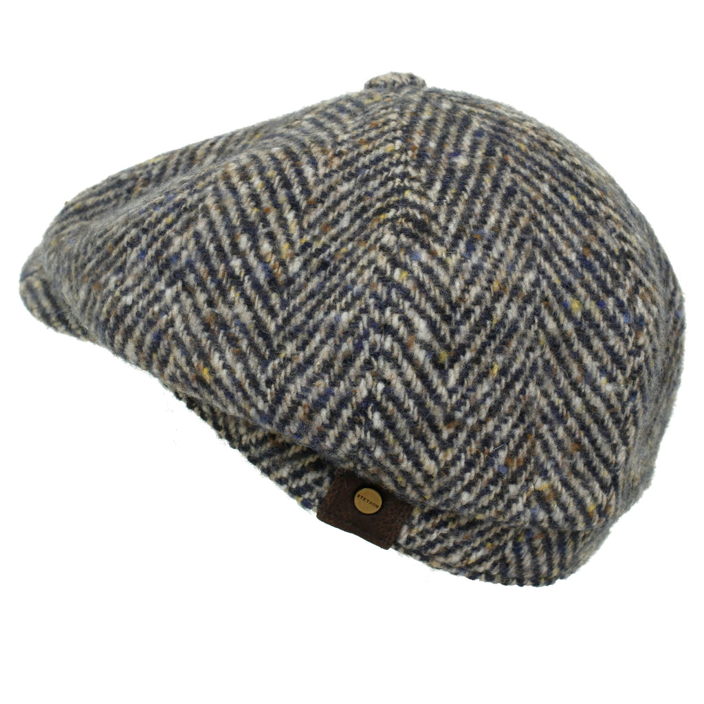 A fashionable grey and brown herringbone tweed flat cap, showcasing its unique pattern.