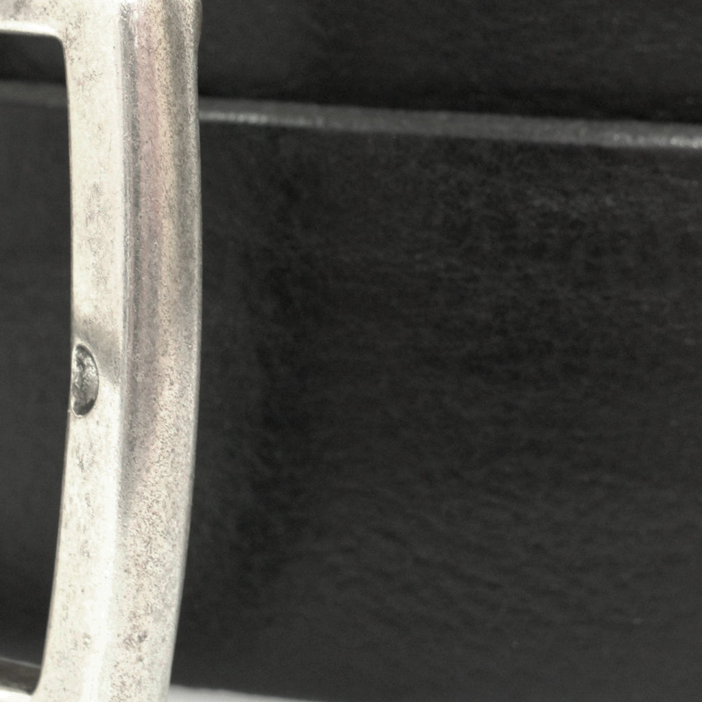 Close-up of a silver belt buckle on a black leather belt, showcasing texture and detail.