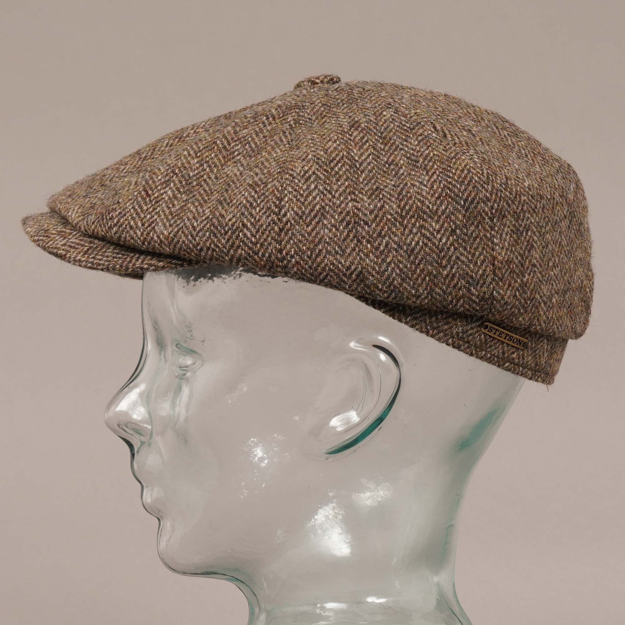 Side profile of a brown herringbone flat cap on a mannequin head.