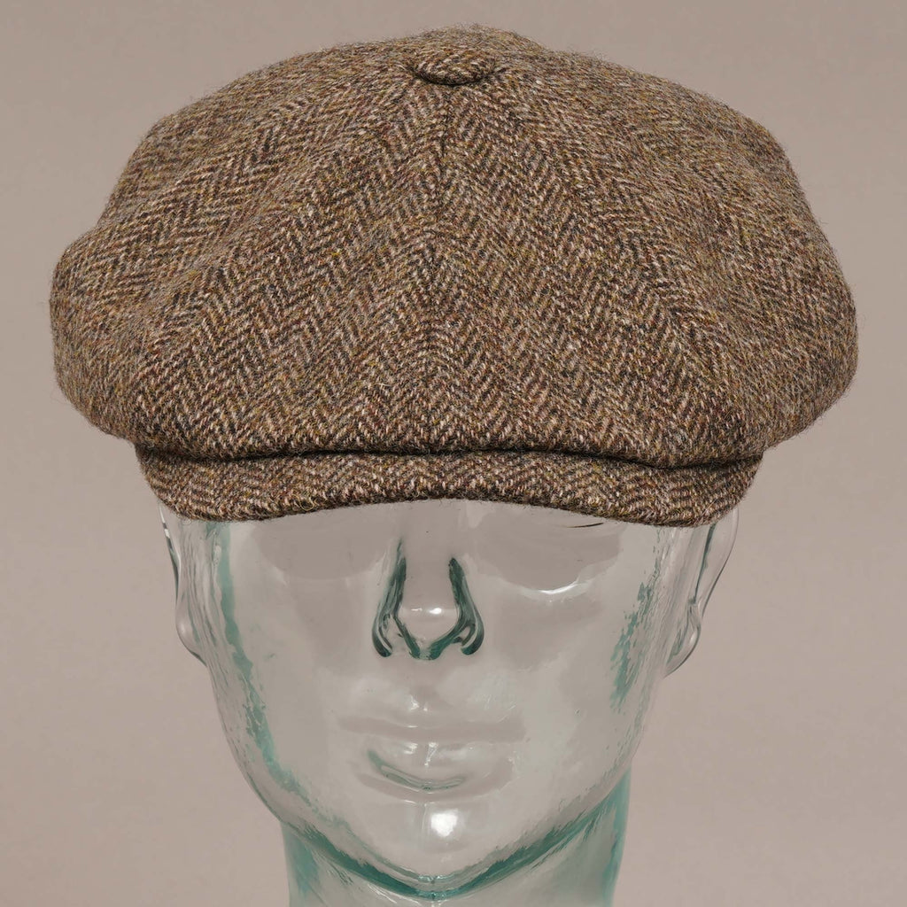 Front view of a brown herringbone flat cap on a mannequin head.