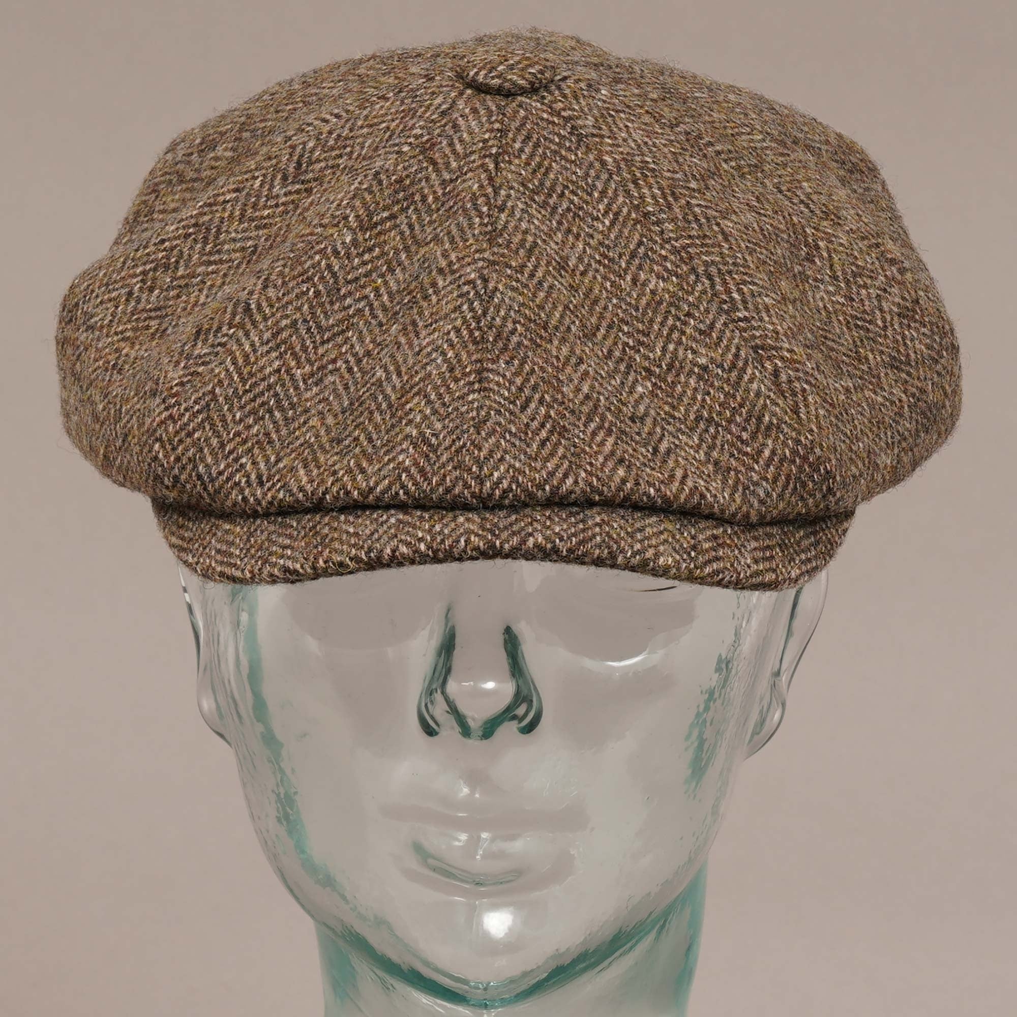 Front view of a brown herringbone flat cap on a mannequin head.
