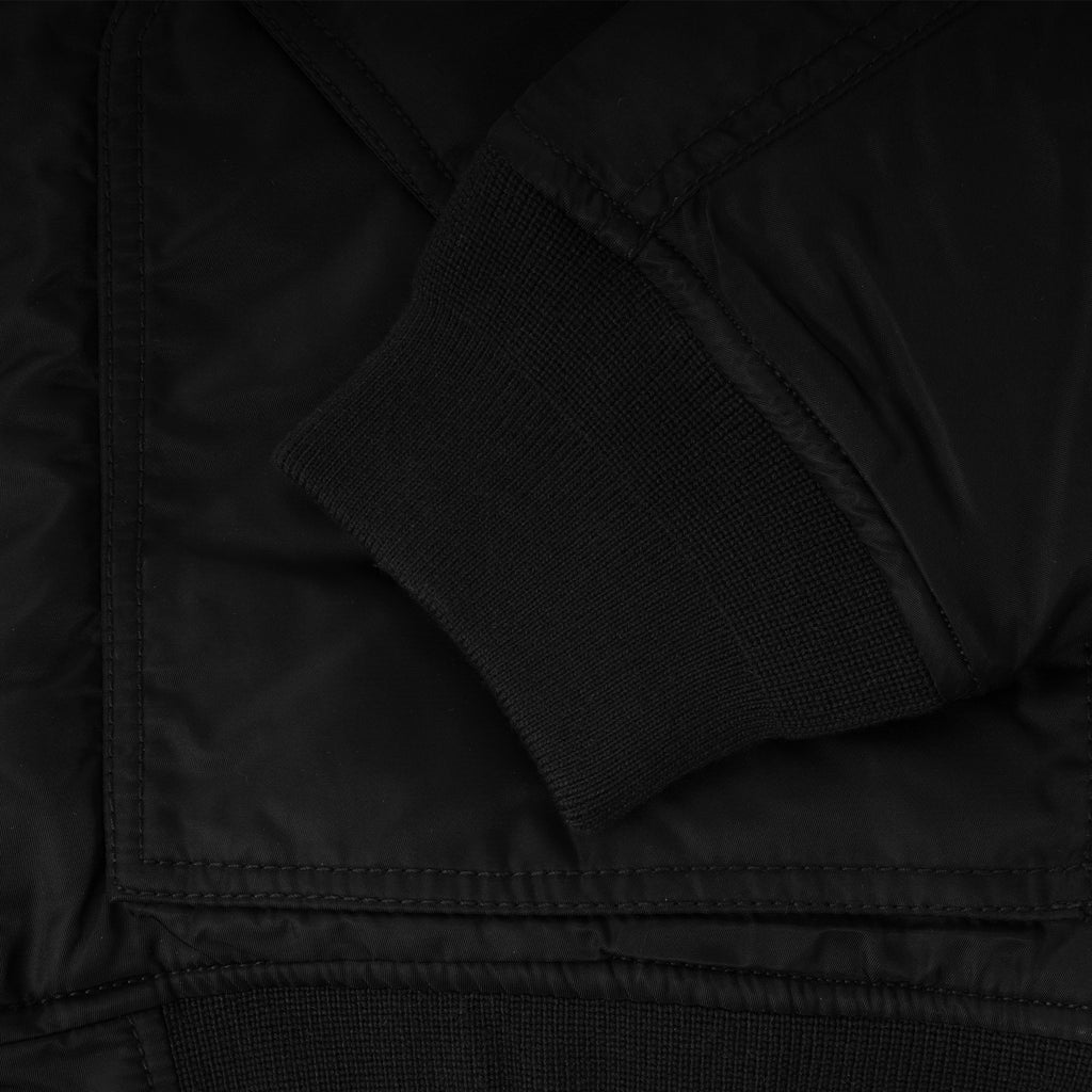 A close-up of the ribbed cuff on the sleeve of a black jacket.