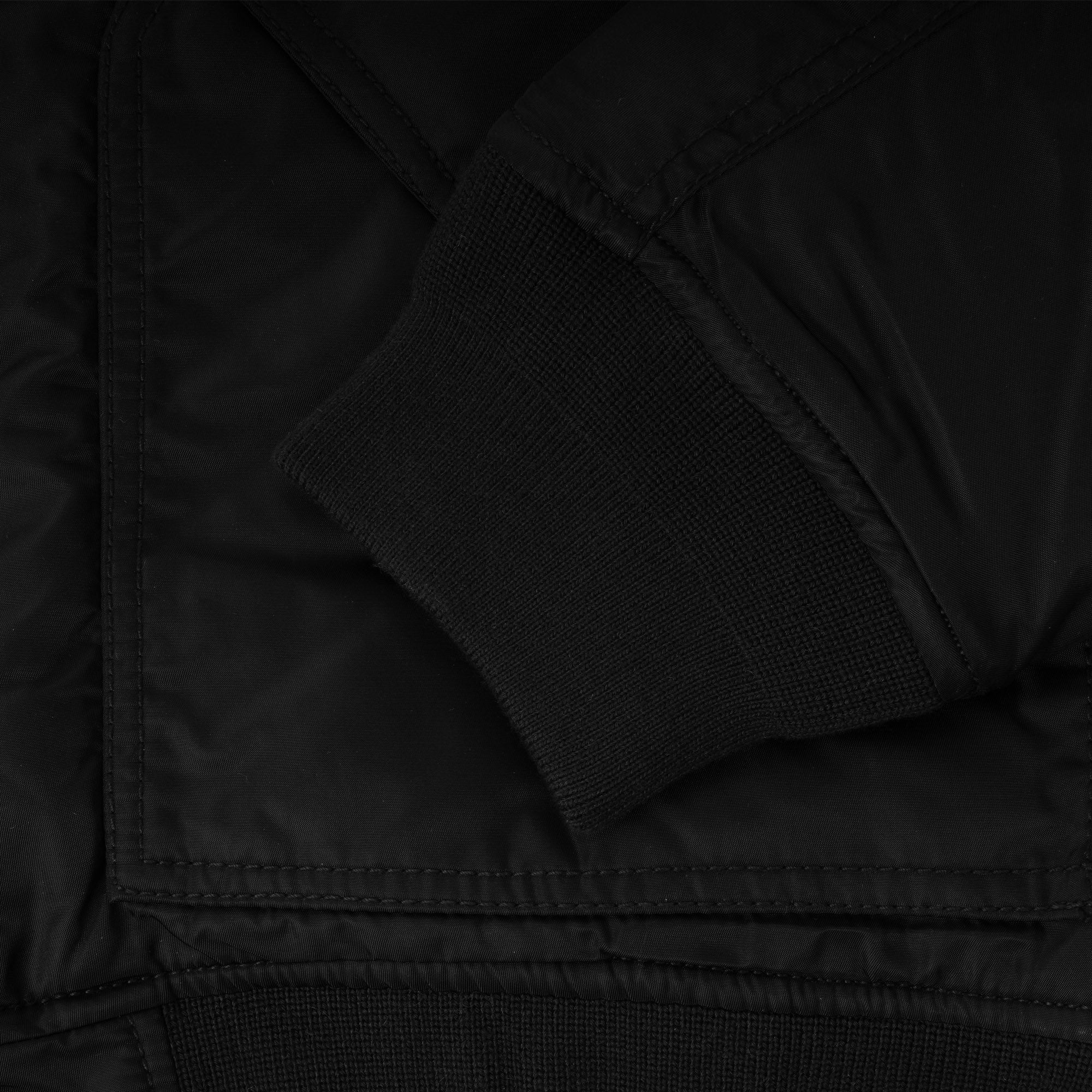 A close-up of the ribbed cuff on the sleeve of a black jacket.