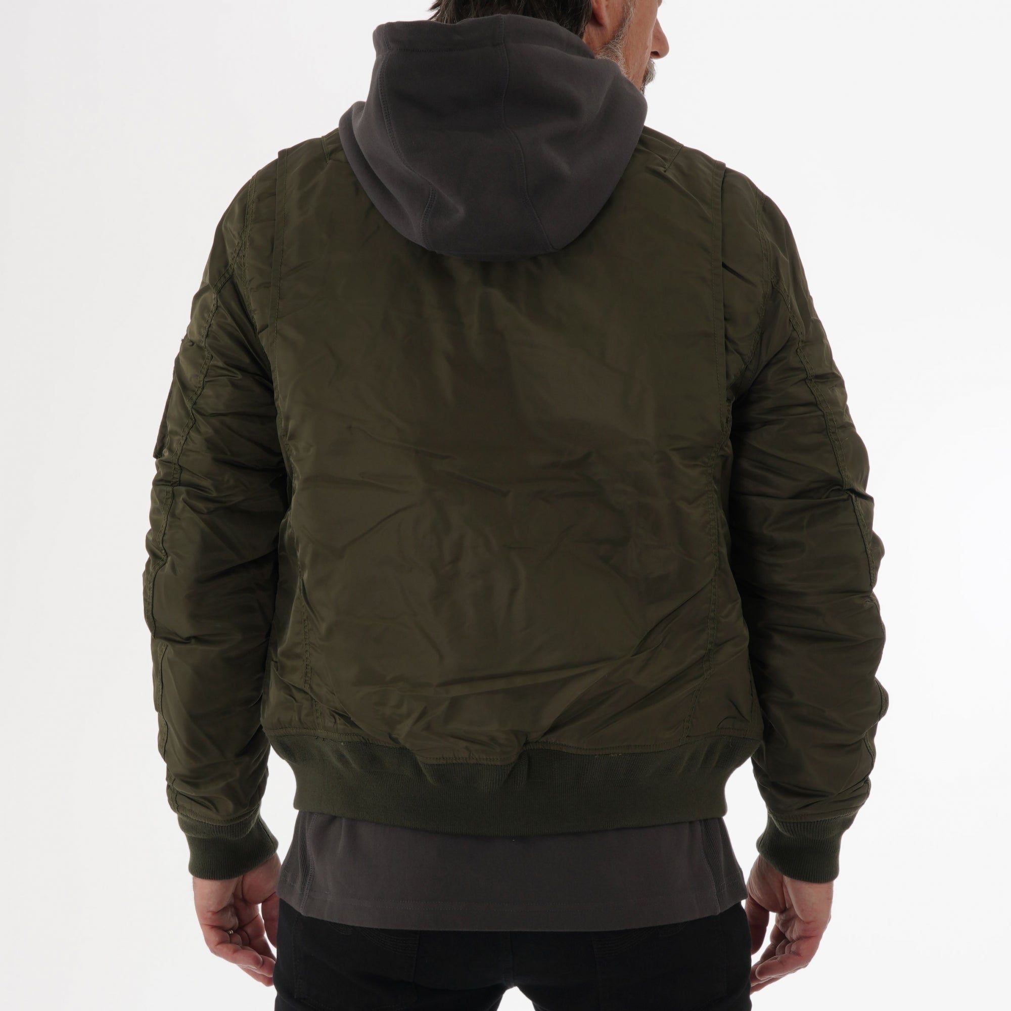 Rear view of a man wearing a khaki bomber jacket over a grey hoodie.