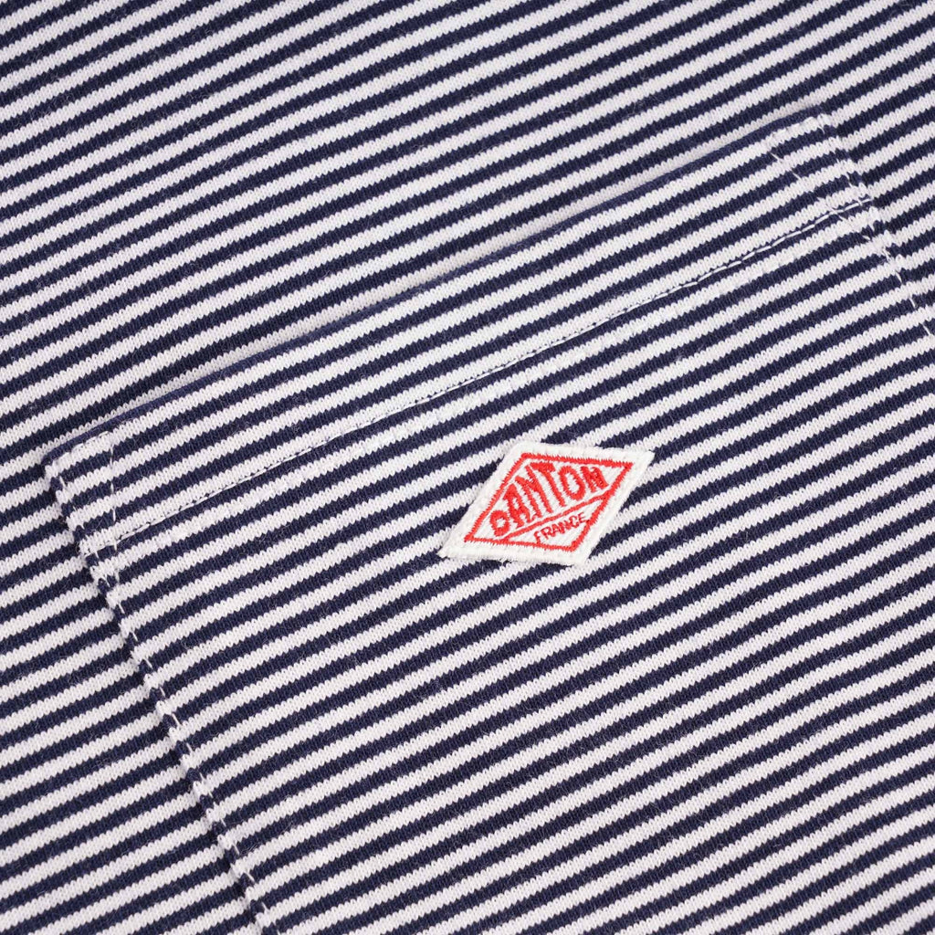 Detail of the red Danone logo on the striped fabric of the T-shirt's chest pocket.