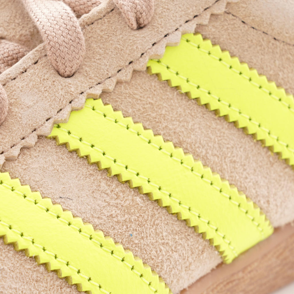 Close-up of the bright yellow serrated three-stripes on the side of the shoe.
