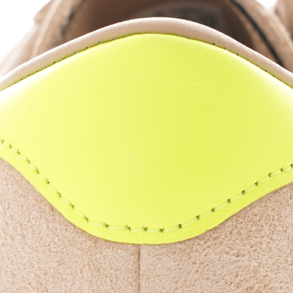 Close-up of the bright yellow heel tab on an Adidas Campus 80s trainer.