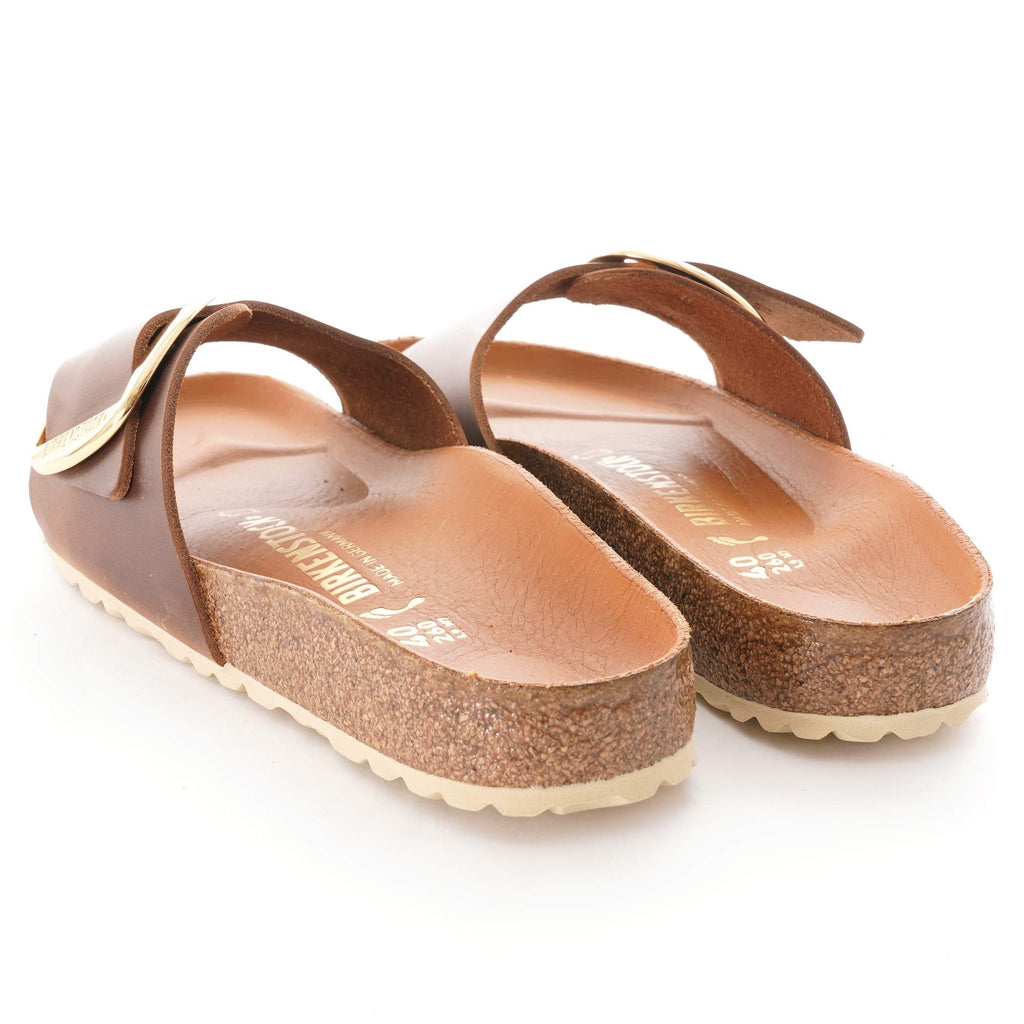 Back view of brown sandals with gold buckles on a white background.