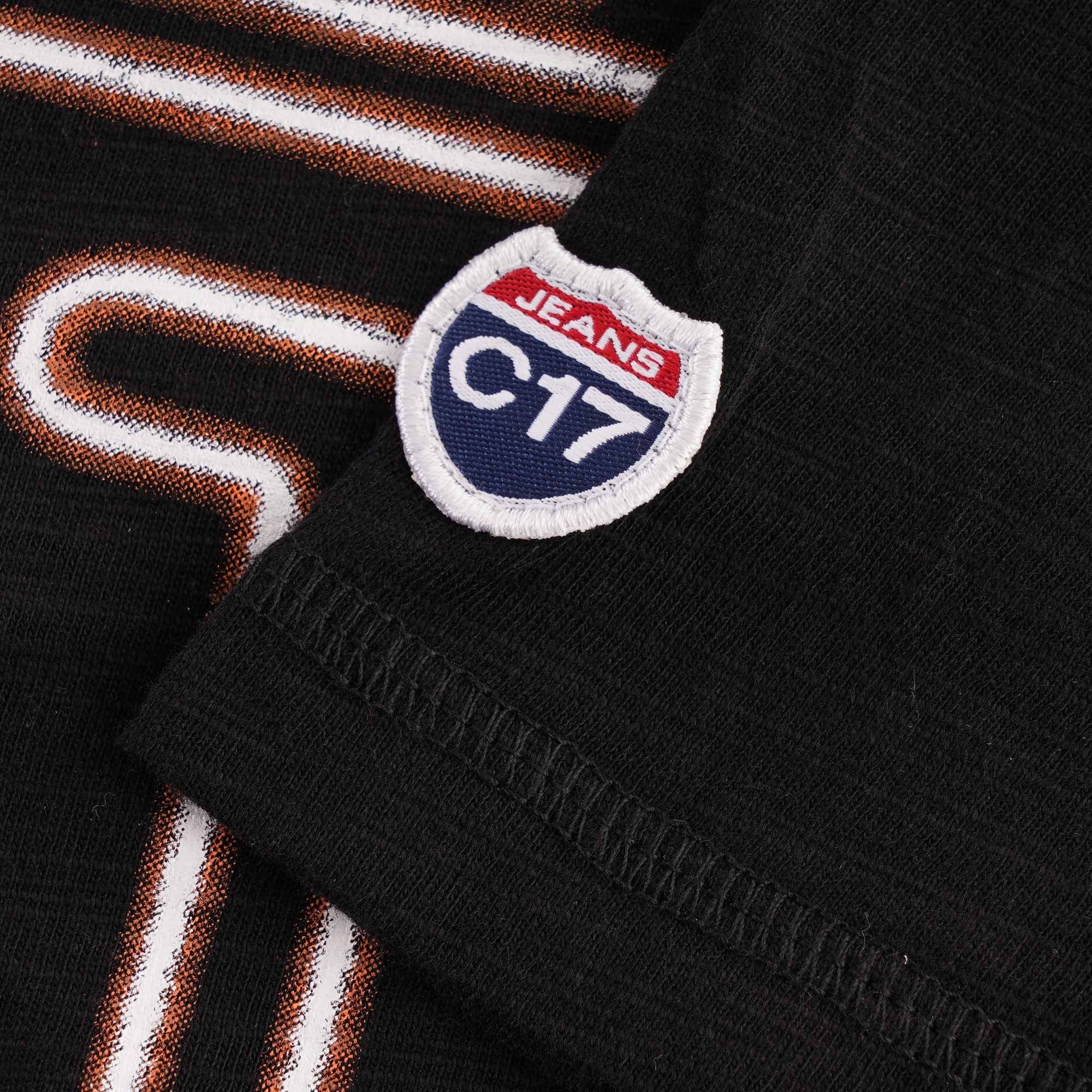 A close up of the C17 Jeans logo on the right sleeve of a black t-shirt.