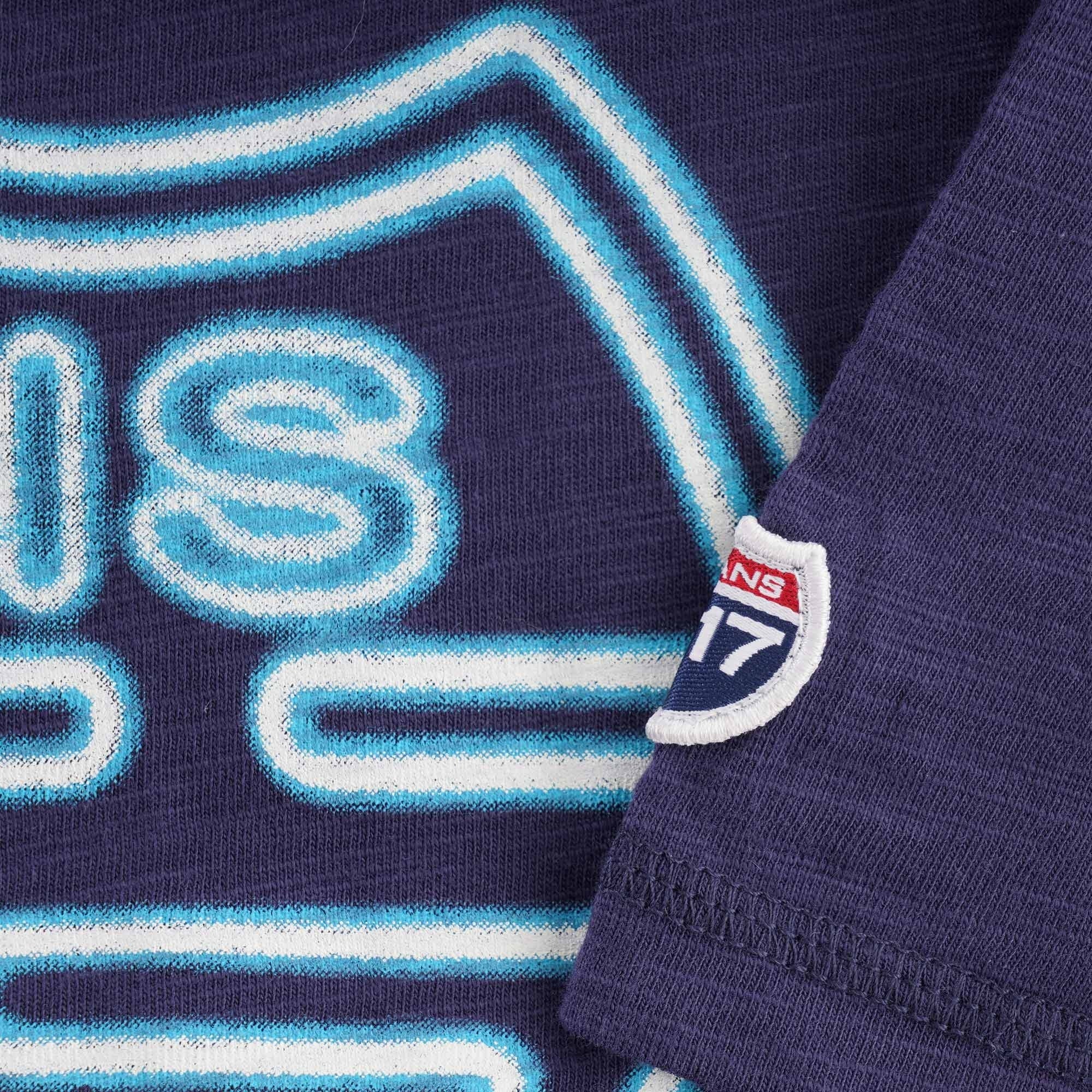 Close-up of the blue neon-style C17 Jeans graphic and brand patch on the sleeve.