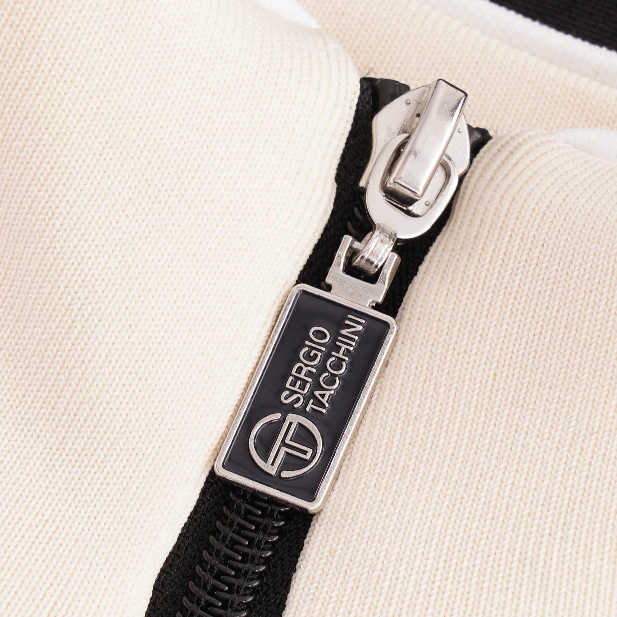 A close-up of the zipper pull with the Sergio Tacchini logo.