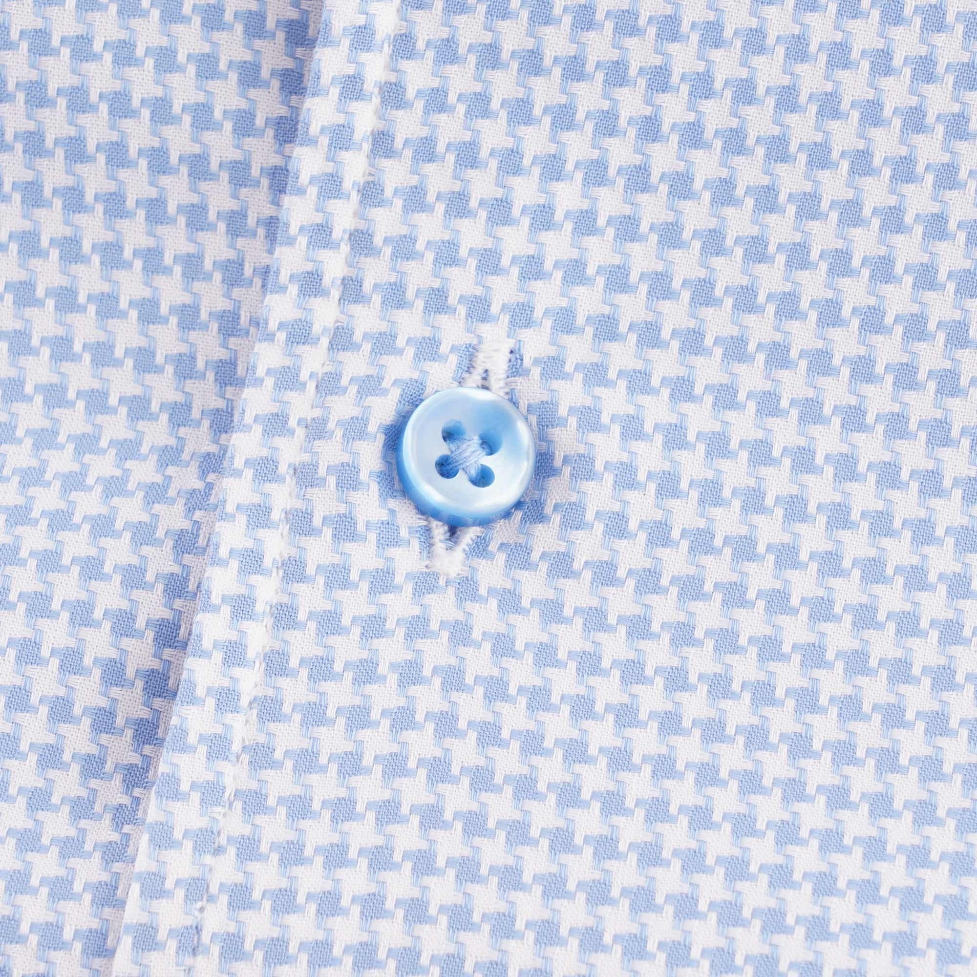 Close-up of a light blue button on the houndstooth patterned short-sleeved shirt.