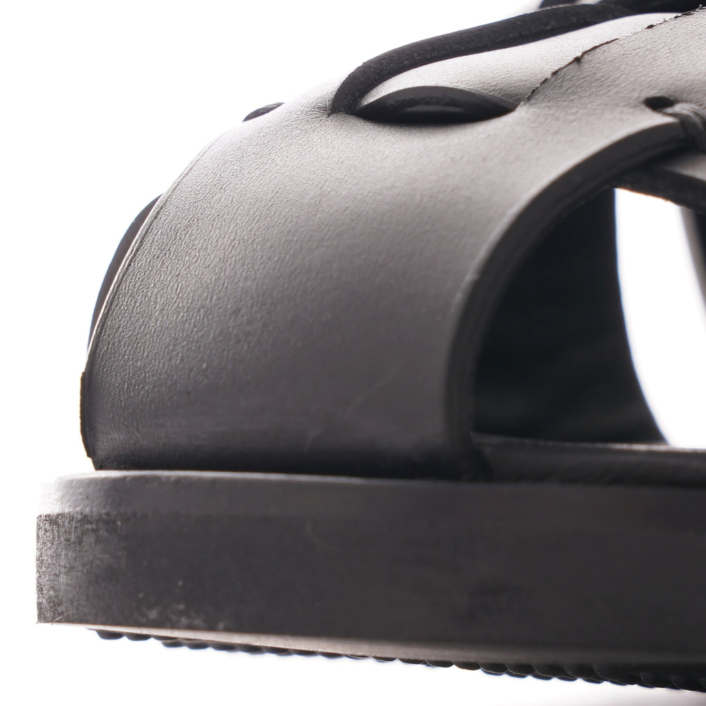 A close-up view of the black leather straps and sole of a fisherman sandal.