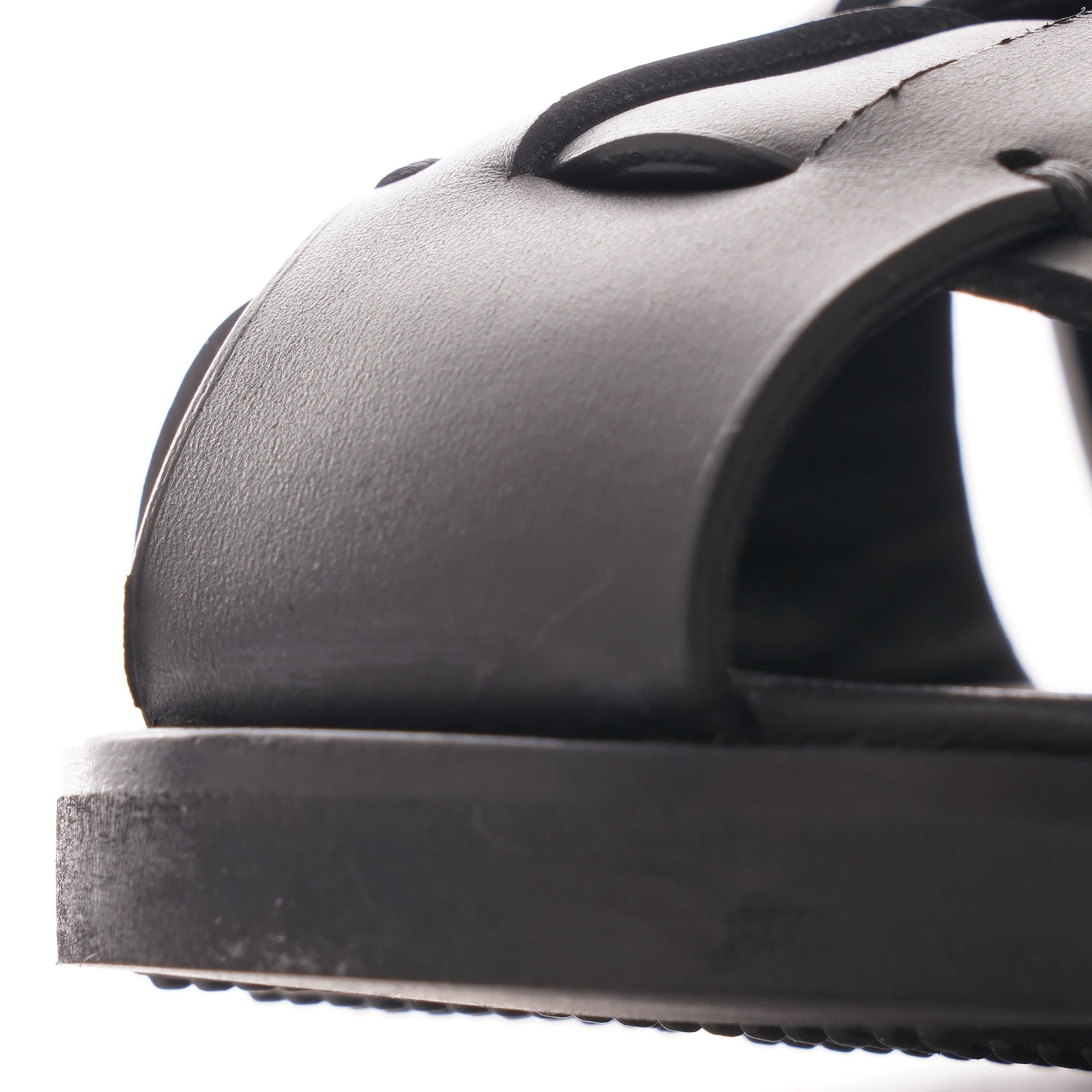 A close-up view of the black leather straps and sole of a fisherman sandal.