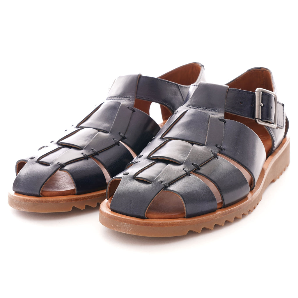 A pair of dark blue leather fisherman's sandals with brown soles, viewed from an angle.