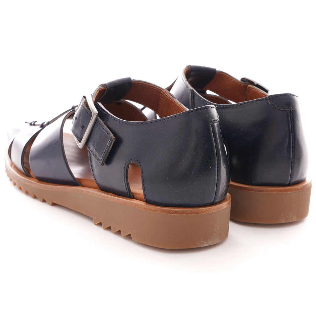 A pair of dark blue leather fisherman's sandals with brown soles, viewed from the rear.