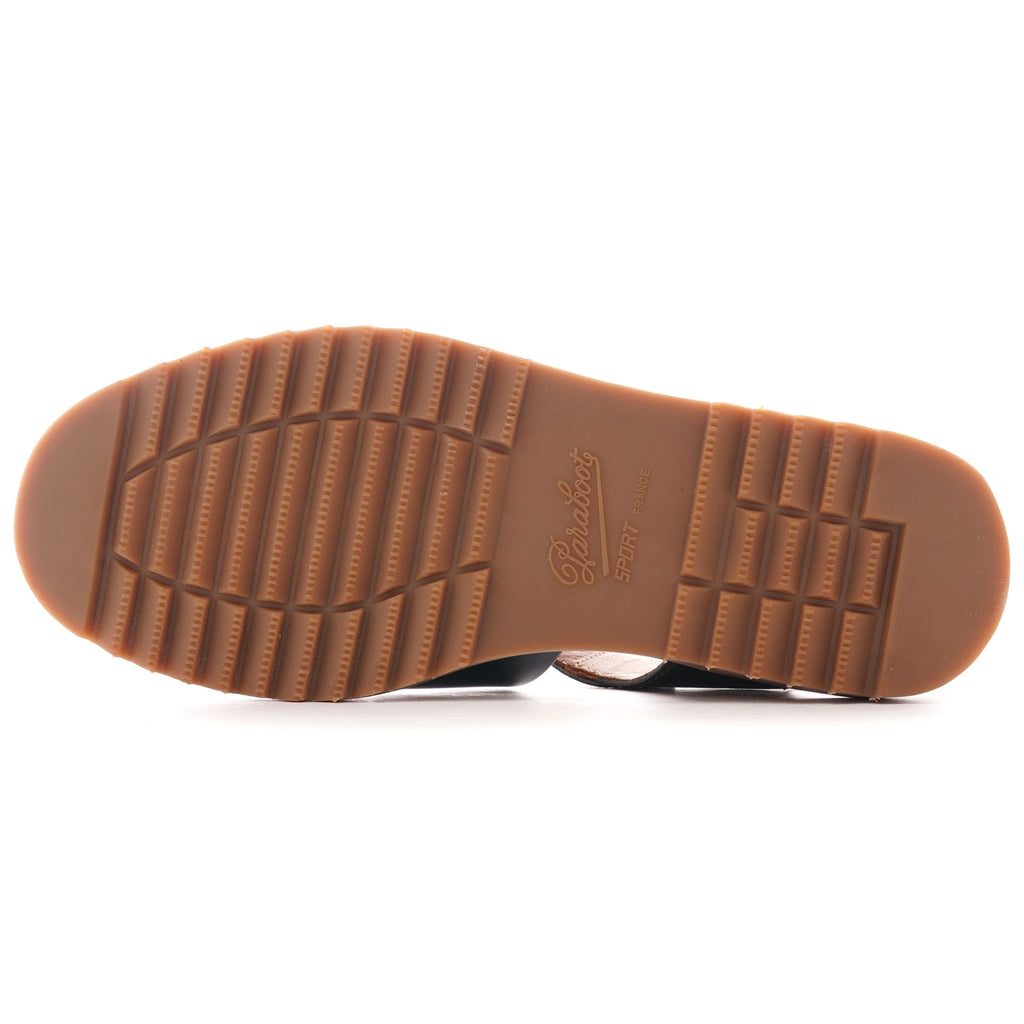 The textured brown sole of a dark blue leather fisherman's sandal.
