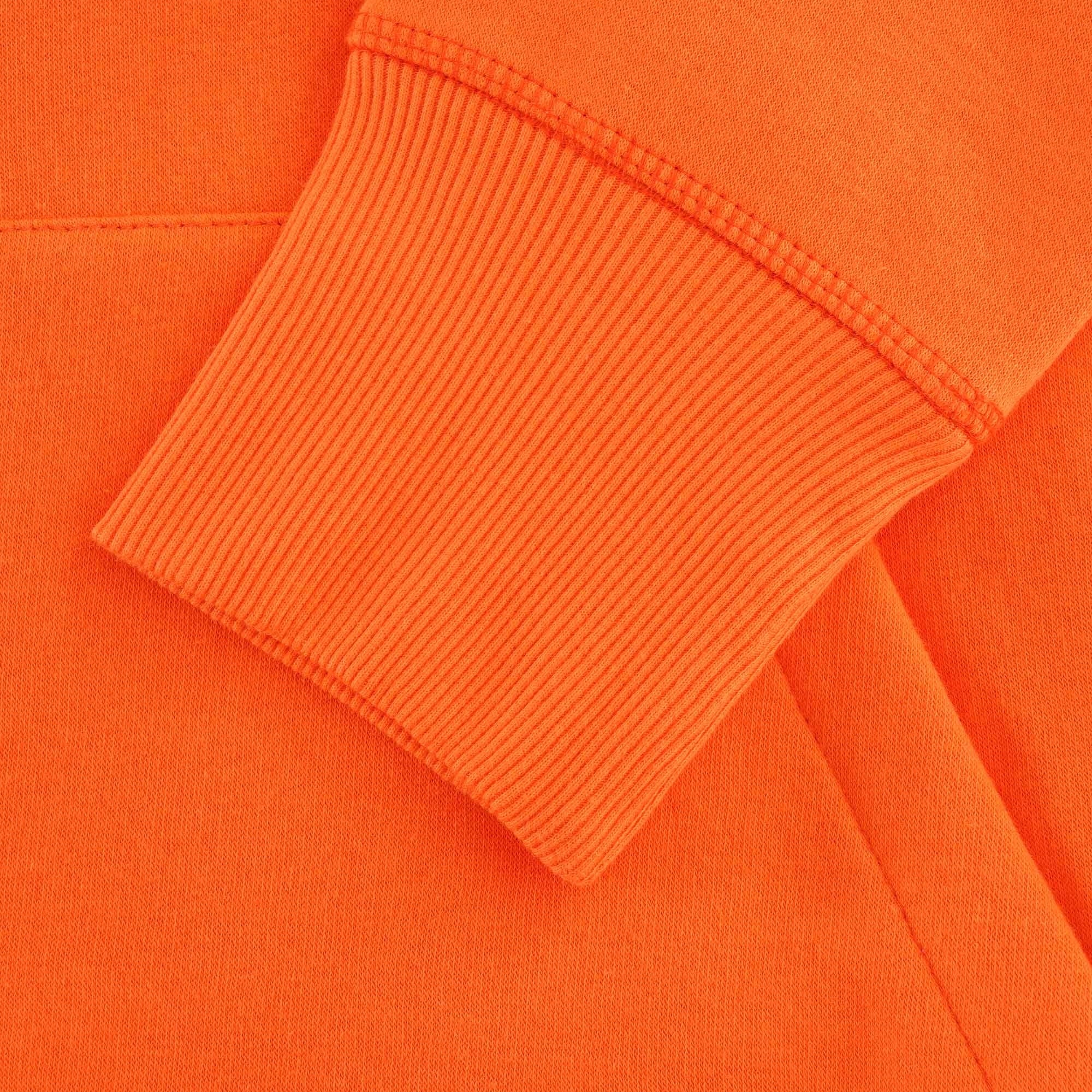 Close-up of the ribbed cuff on the orange hoodie's sleeve.