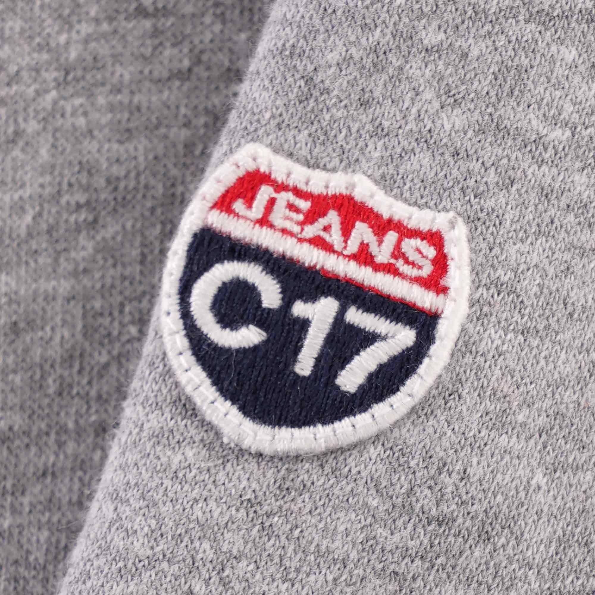A close-up of the C17 Jeans patch on the sleeve of the grey hoodie.