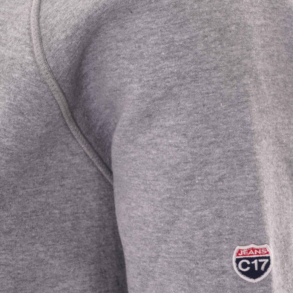 Close-up of the C17 brand logo embroidered on the sleeve of the grey sweatshirt.