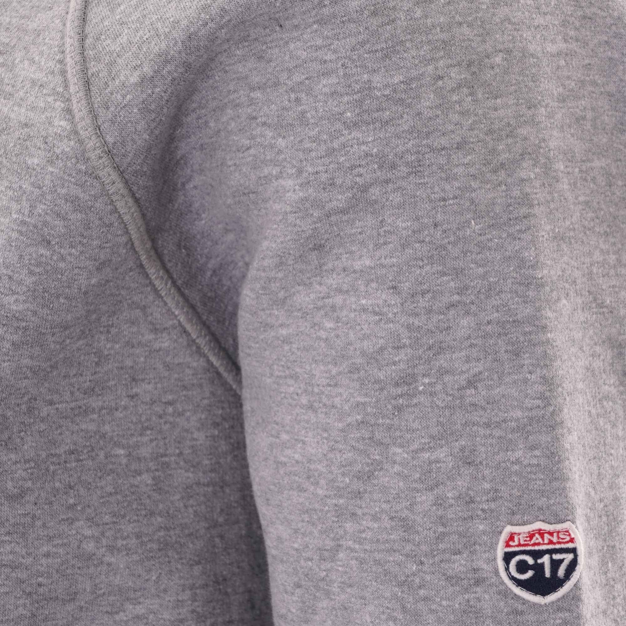 Close-up of the C17 brand logo embroidered on the sleeve of the grey sweatshirt.