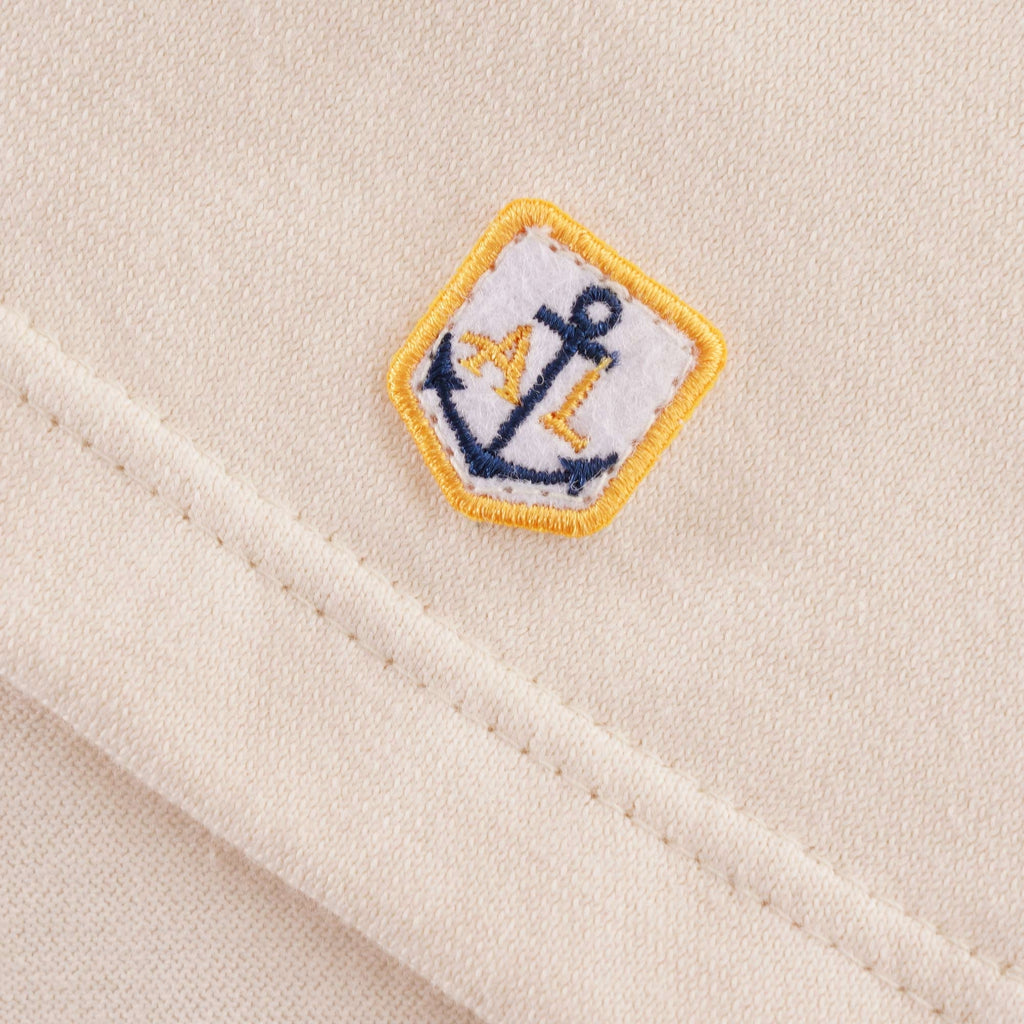 A detailed view of the small anchor logo on the bottom hem of the Loctudy T-Shirt.
