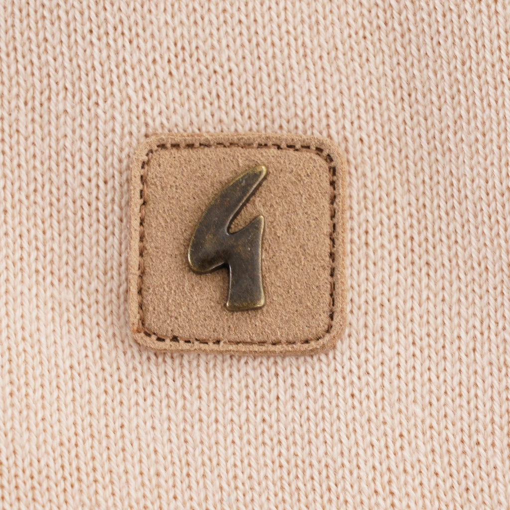 A close up of the logo on a beige polo shirt with a red trim.