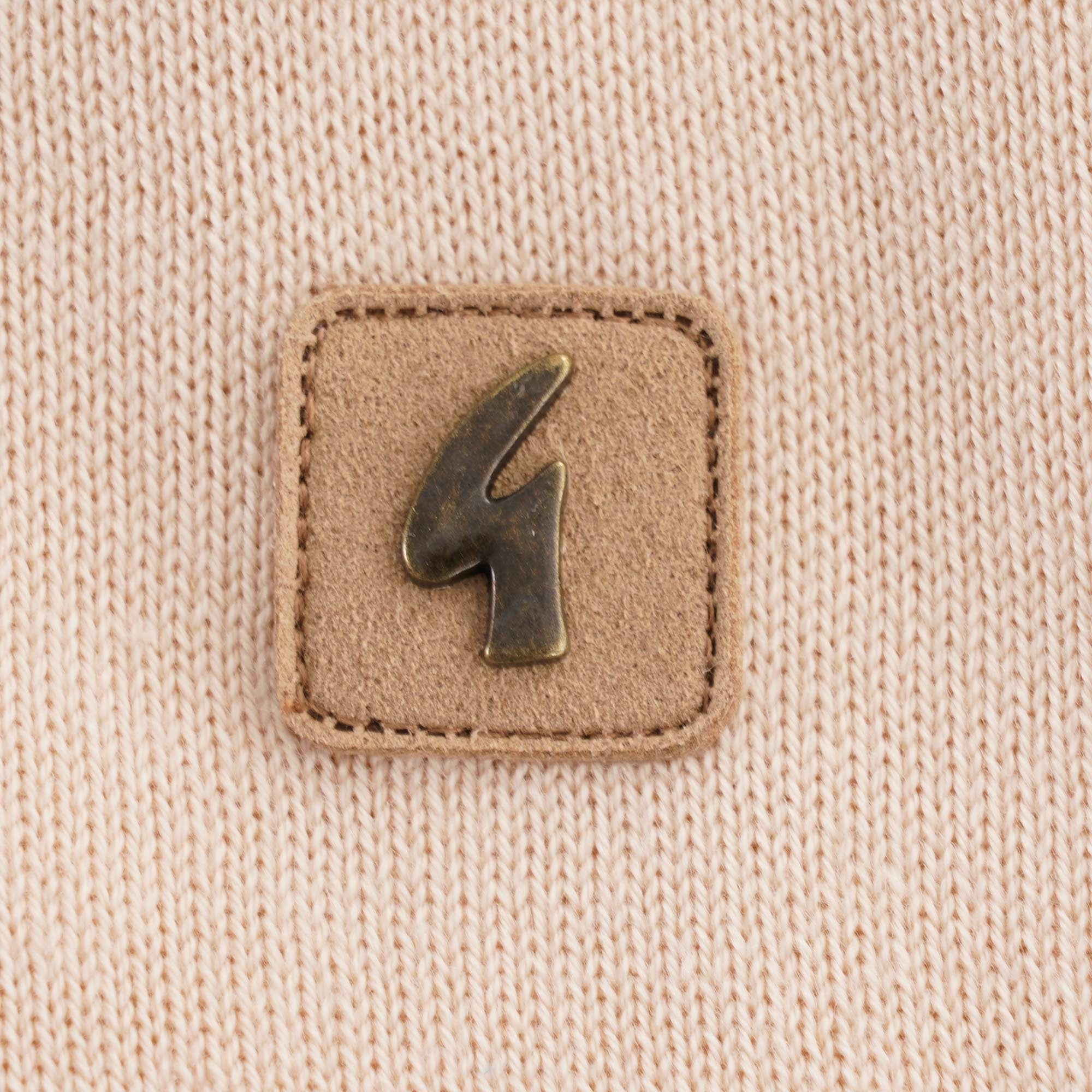 A close up of the logo on a beige polo shirt with a red trim.