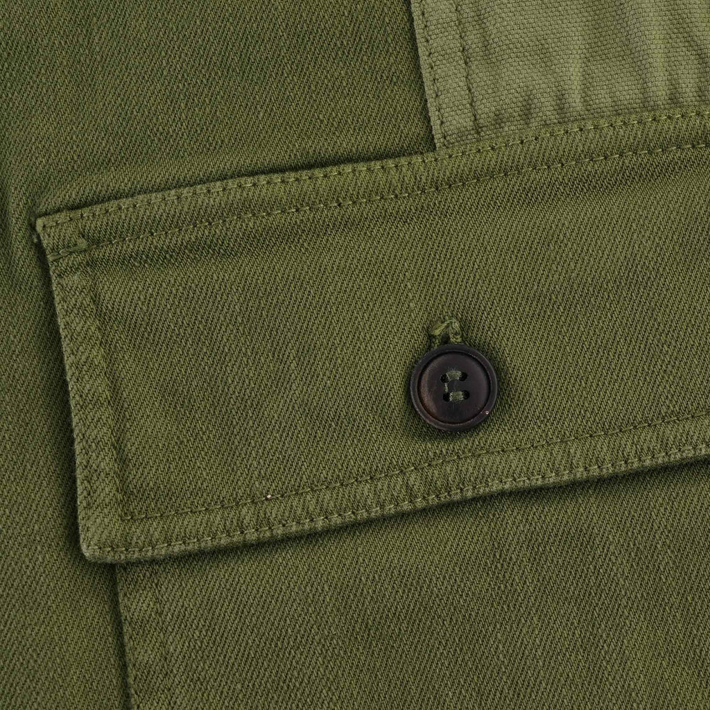 Detail of a buttoned pocket on an olive green waistcoat.