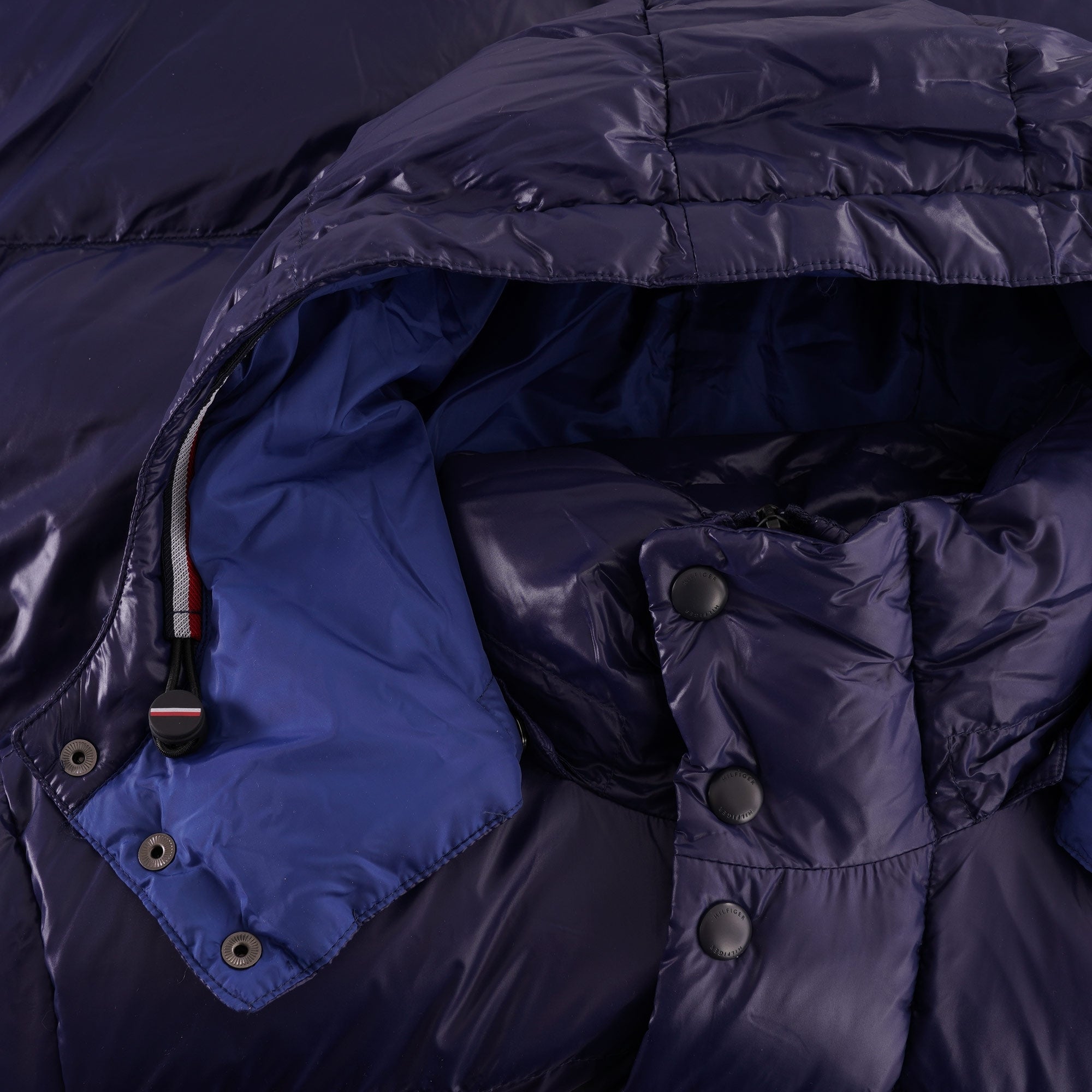 A close-up of the navy blue puffer jacket's hood, showing the blue lining and snap buttons.