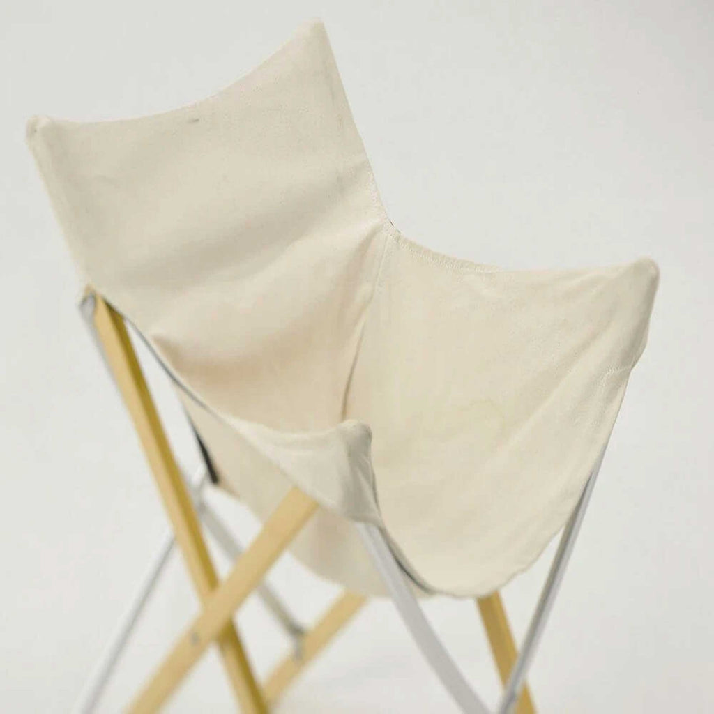 A close-up of the seat and backrest of the white canvas folding chair.