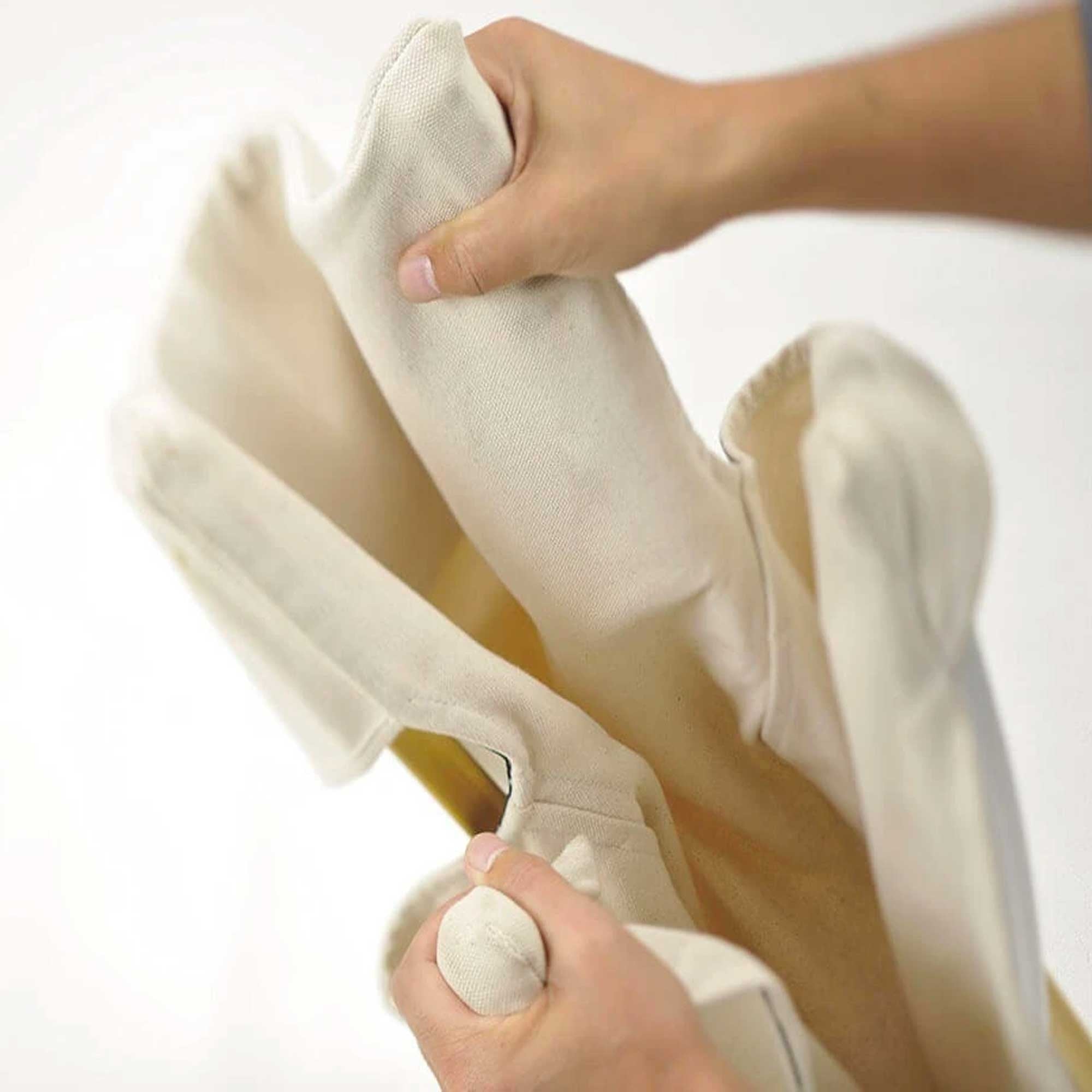 Hands continuing to fold the chair, gathering the canvas and frame.