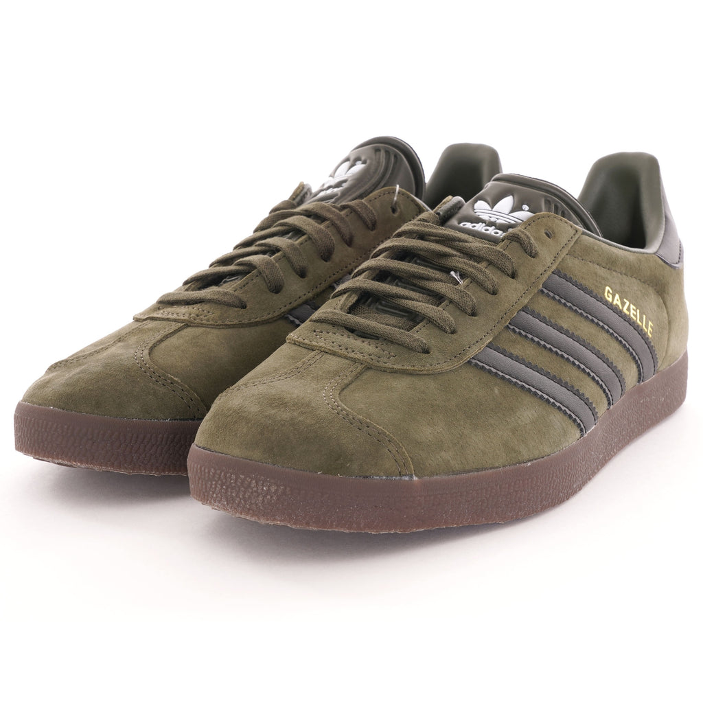 A pair of olive green suede Adidas Gazelle trainers with black stripes and brown soles. 
