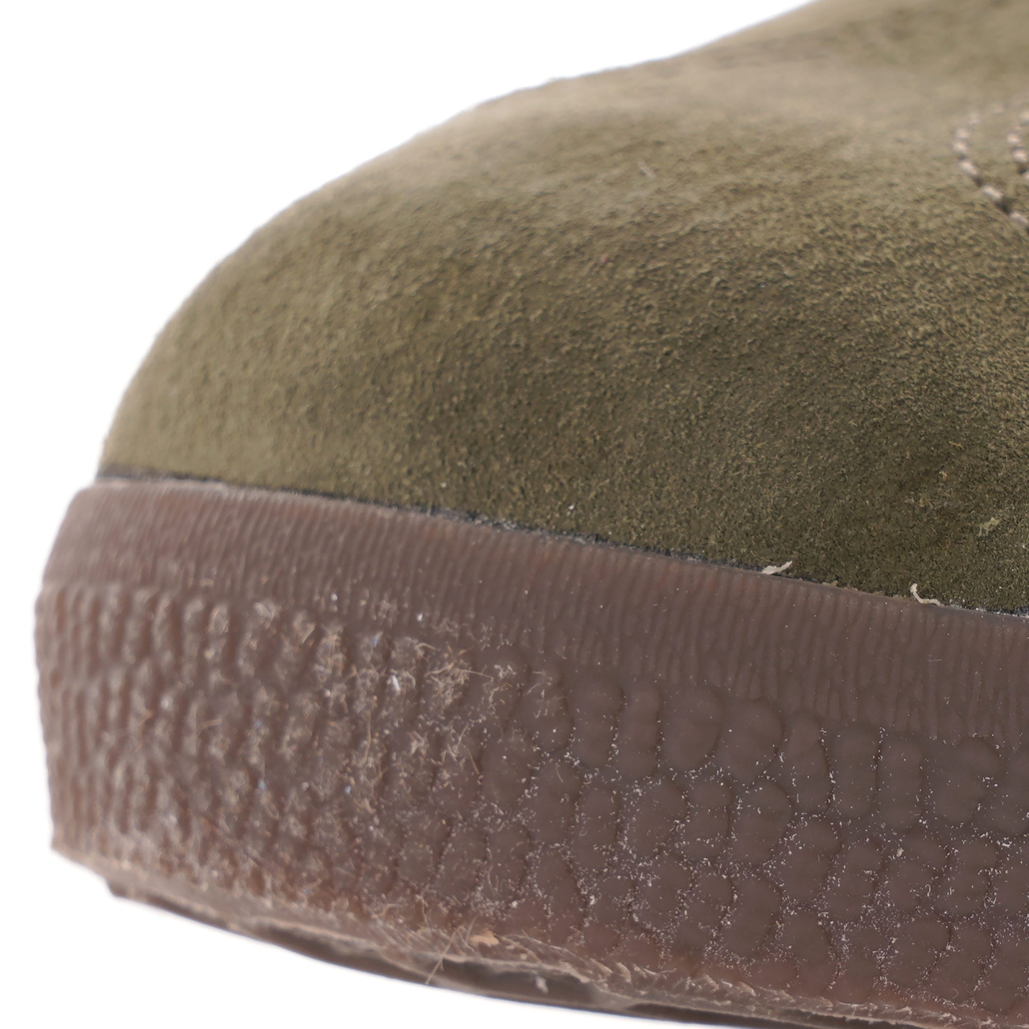 A close-up of the toe of an olive green Adidas Gazelle trainer with a brown textured sole. 