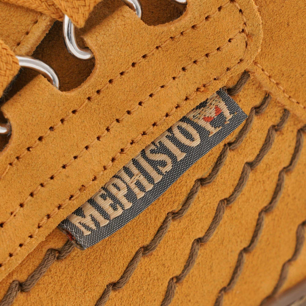 Close-up of the Mephisto brand tag on the side of a mustard yellow 'Rainbow' shoe.
