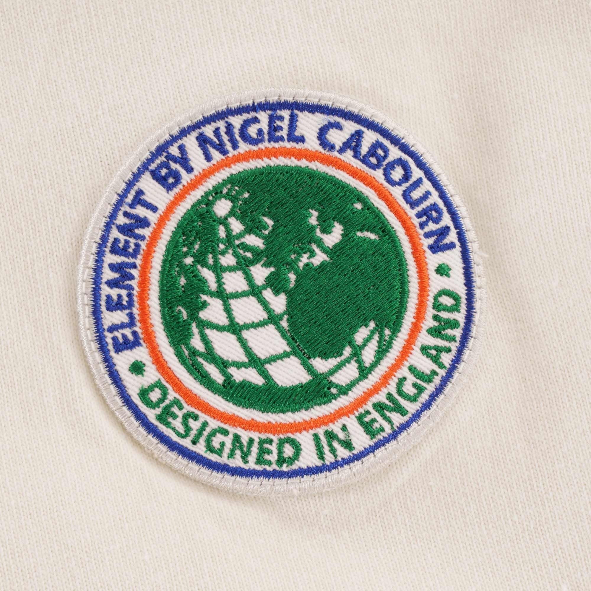 A close-up of the circular chest logo, featuring a globe design and text.