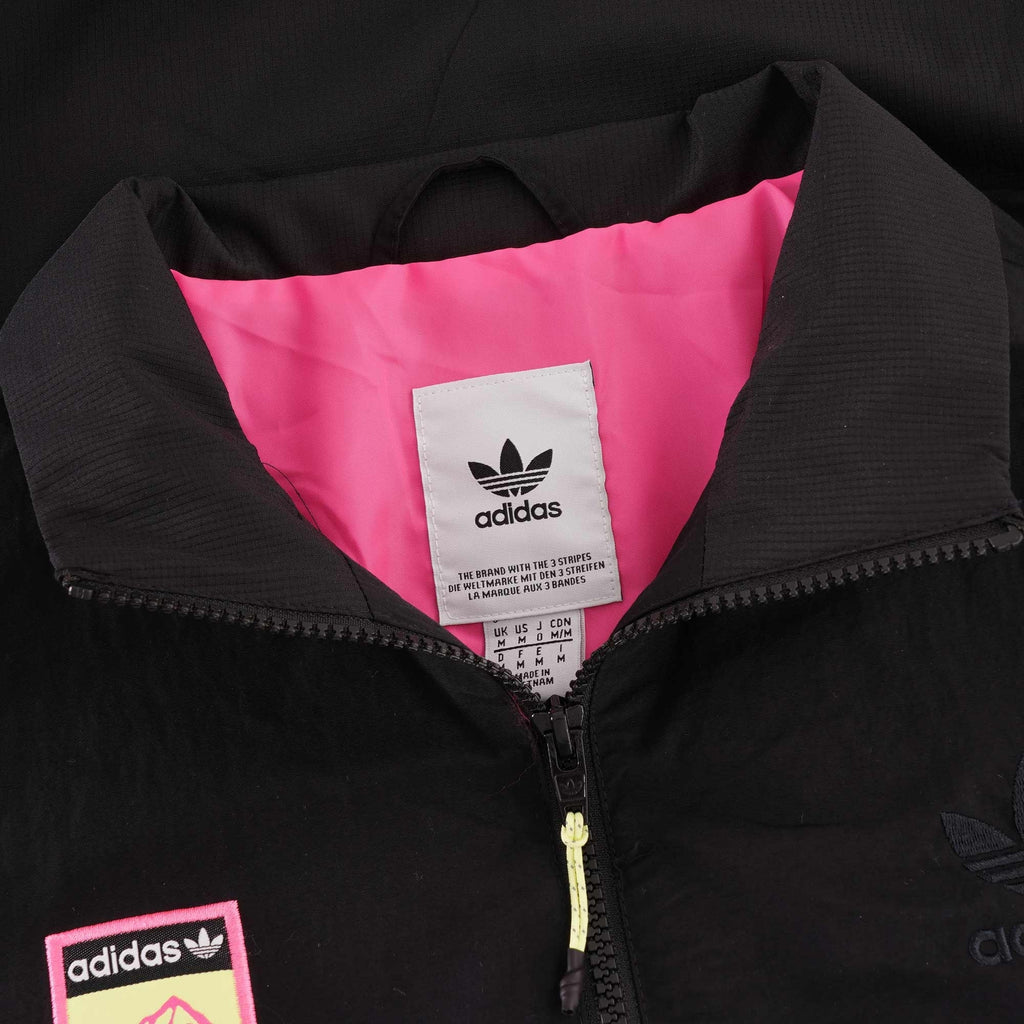 The collar of a black Adidas jacket, showing the pink interior and Adidas neck label.