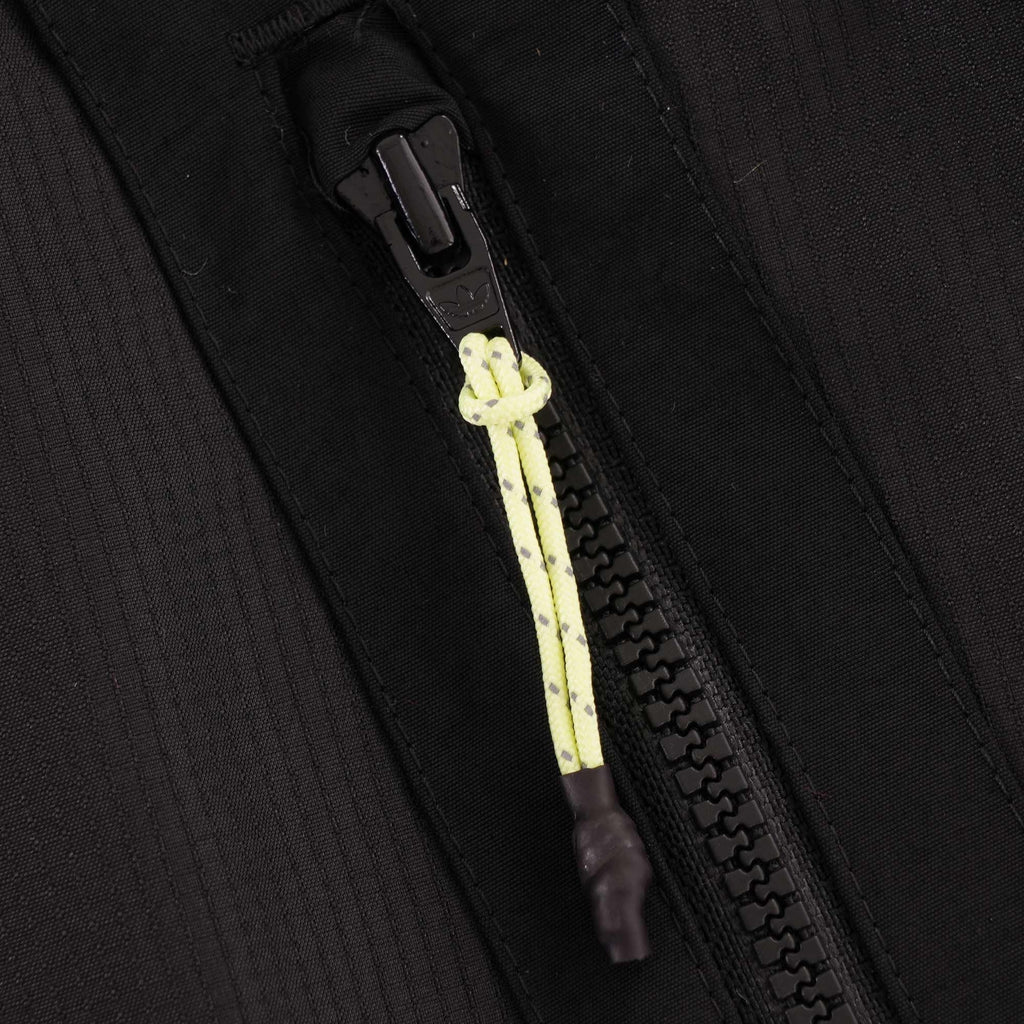 A close-up of the black zipper on the jacket, with a yellow and black cord puller.
