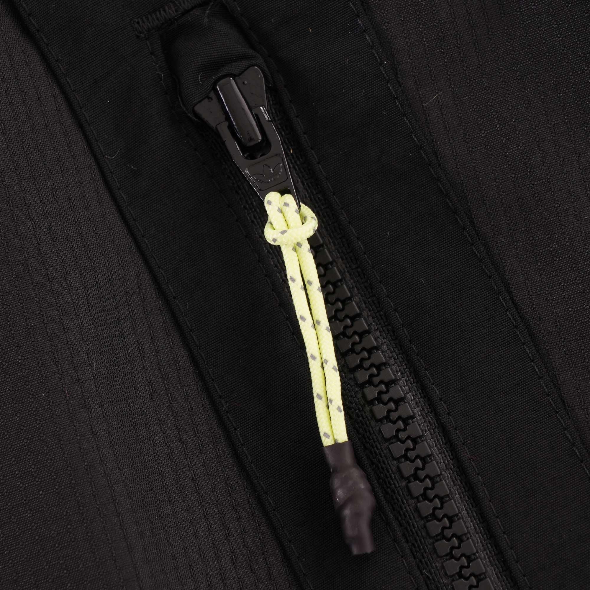 A close-up of the black zipper on the jacket, with a yellow and black cord puller.