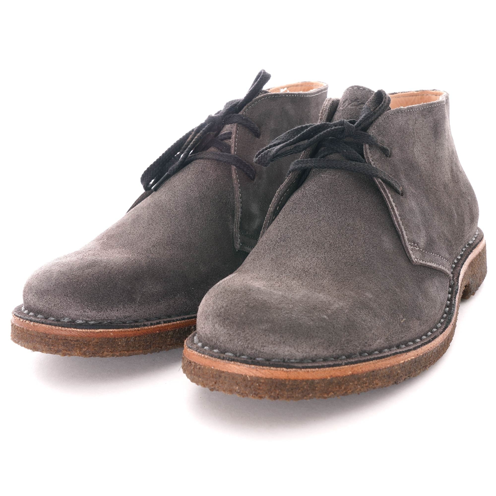 Pair of grey suede desert boots with black laces and brown soles.