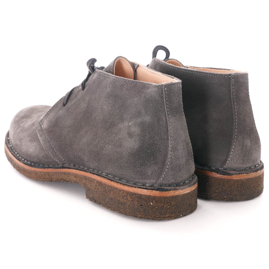 Rear view of a pair of grey suede desert boots with brown soles.