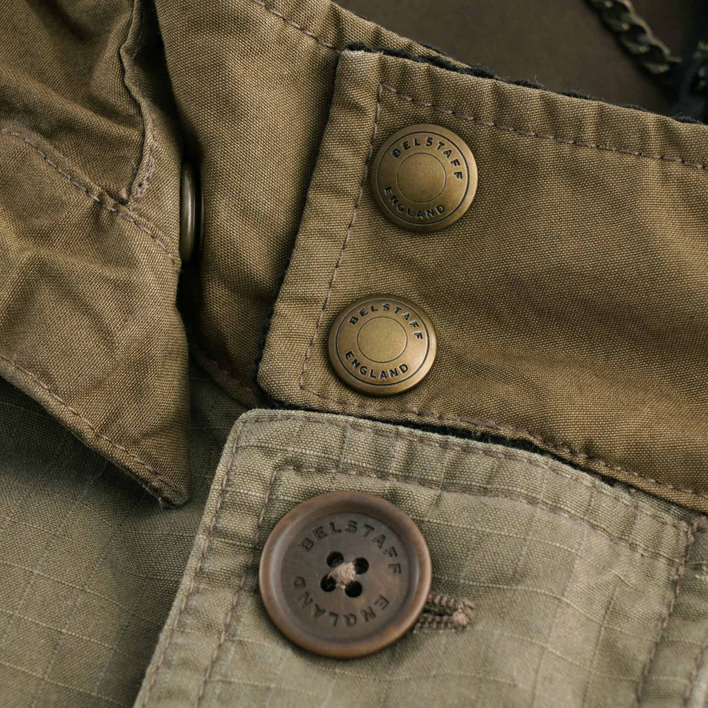 Detail of the jacket's press studs and button, both branded 'BELSTAFF ENGLAND'.