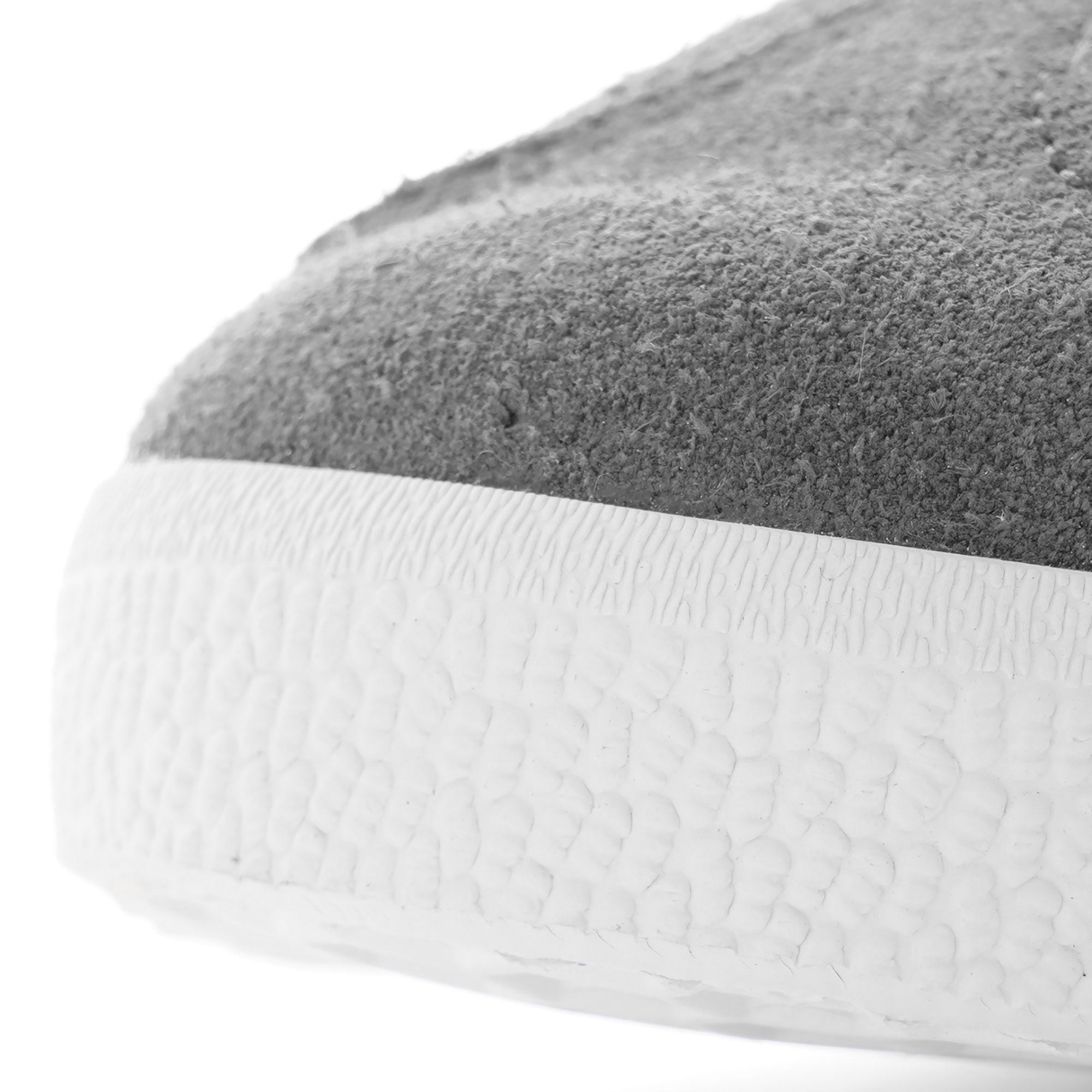 Close-up of the textured white sole and grey suede toe of an Adidas Gazelle trainer.