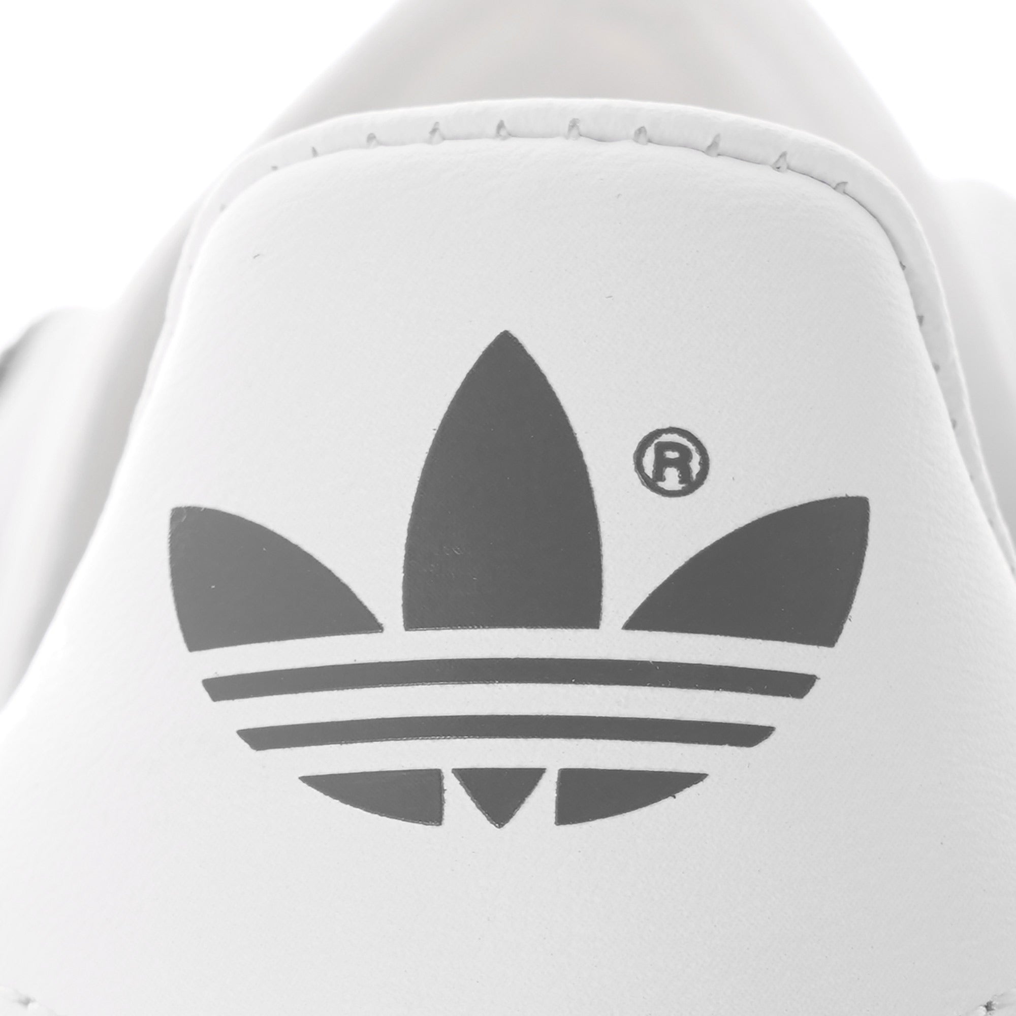 Close-up of the Adidas Trefoil logo on the white heel of a trainer.