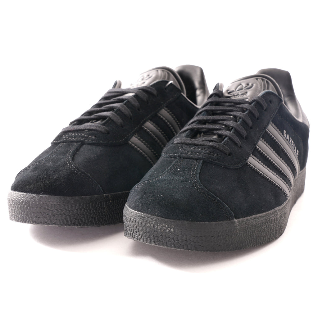 A pair of black Adidas Gazelle trainers, photographed from an angled front view.