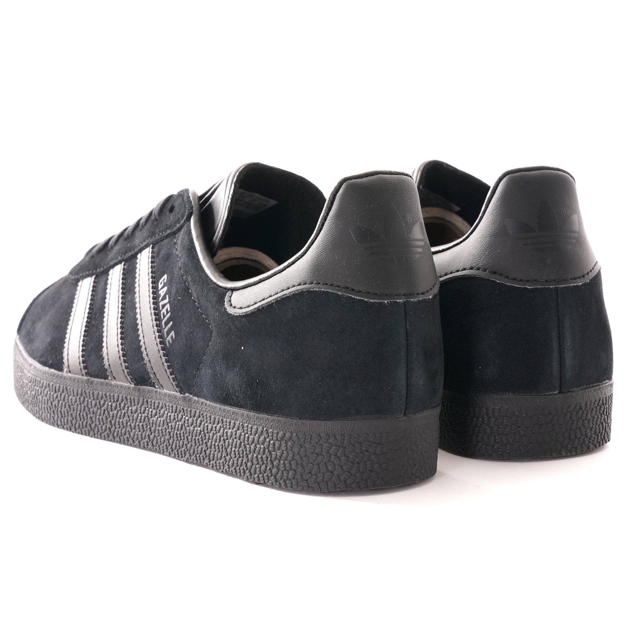 A pair of black Adidas Gazelle trainers, photographed from an angled rear view.