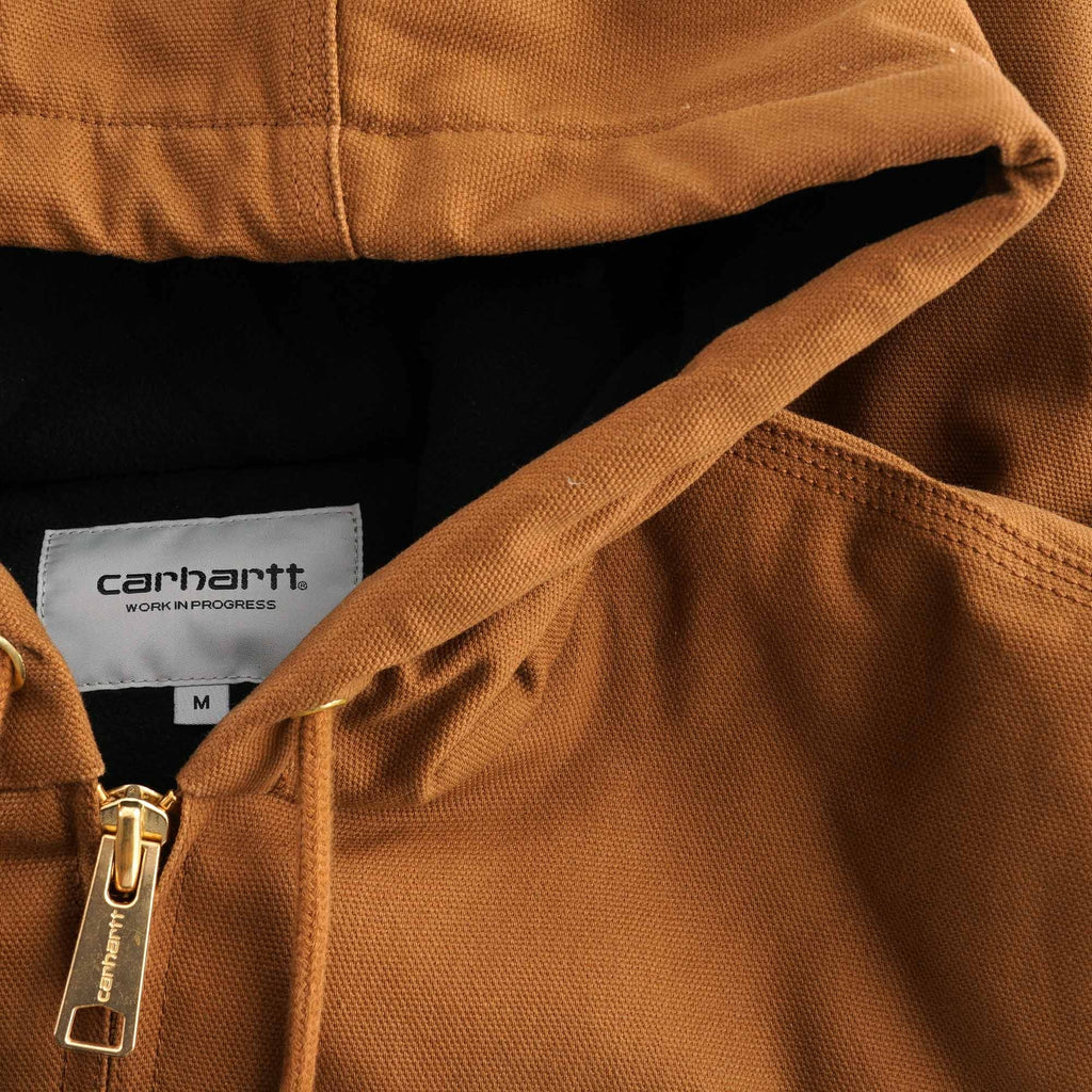 Close-up of a brown Carhartt jacket showing the hood, zip, and label.