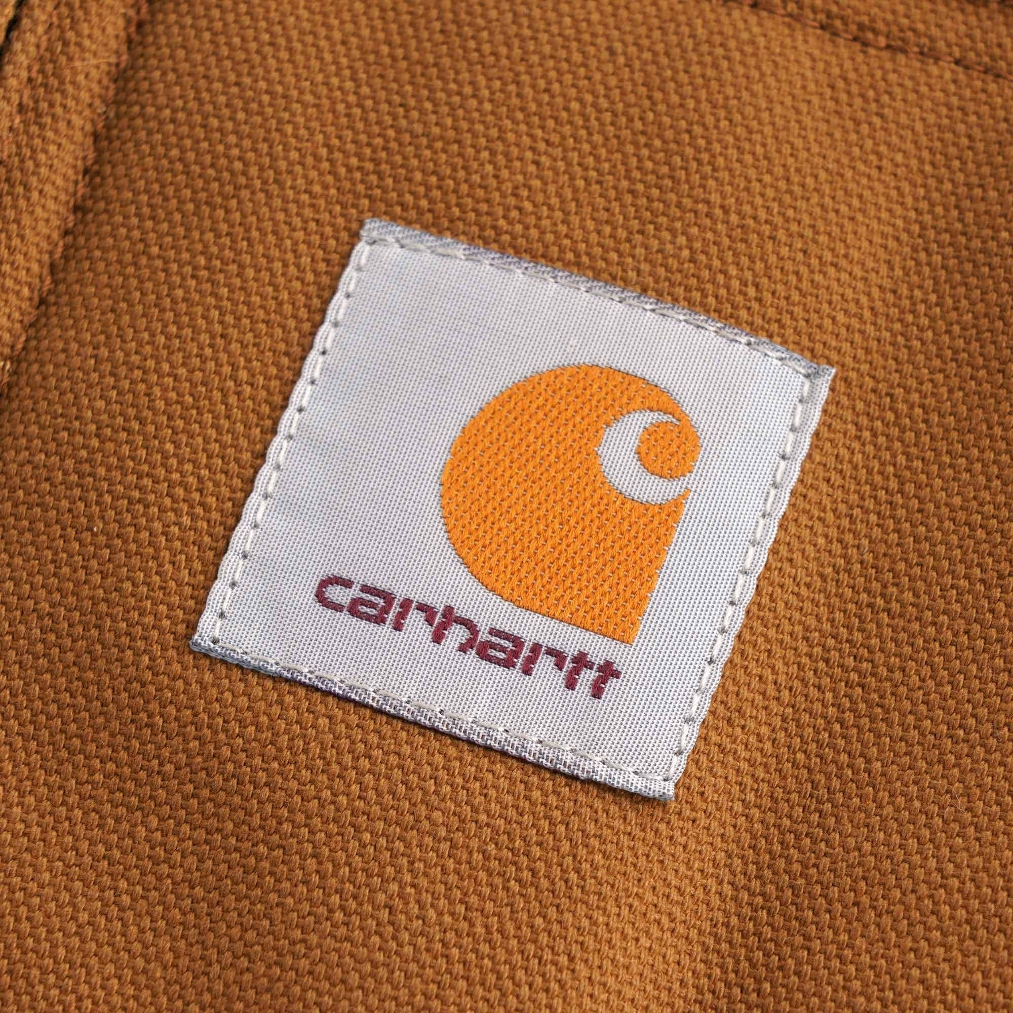 Close-up of the Carhartt logo patch on a brown jacket pocket.