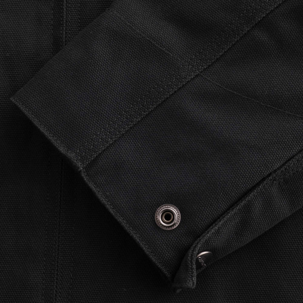 A close-up of the cuff of a black jacket with a snap button detail.
